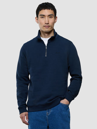 A man wearing a Sweat Half Zip Dark Navy over a white t-shirt and blue jeans.