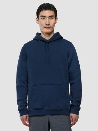 A man wearing a Sweat Hoodie Dark Navy with a front kangaroo pocket.