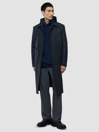 A man wearing a dark overcoat over a Sweat Hoodie Dark Navy and grey trousers.