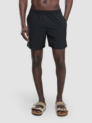 A person wearing Swim Shorts Black and tan two-strap sandals.