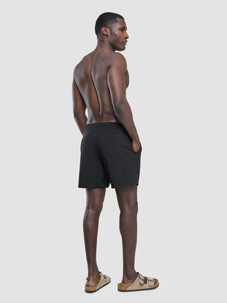 A shirtless man viewed from behind, wearing Swim Shorts Black and sandals.
