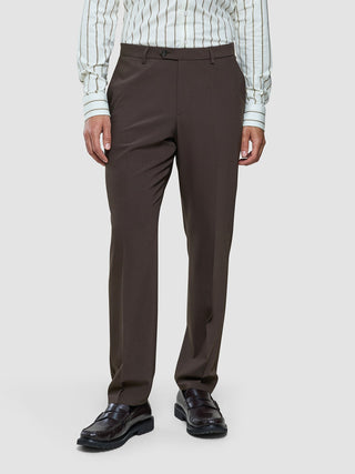 A person wearing a striped button-down shirt, Tech Wool Suit Pants Regular Cocoa Brown, and dark leather loafers.