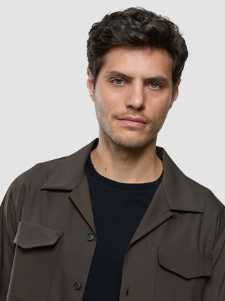 A man wearing a Tech Wool Overshirt Cocoa Brown over a black t-shirt.