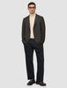 A man wearing a Timeless Wool Blazer Slim Dark Brown Check over a beige turtleneck sweater, dark trousers, and loafers.