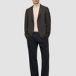 A man wearing a Timeless Wool Blazer Slim Dark Brown Check over a beige turtleneck sweater, dark trousers, and loafers.