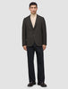 A person wearing a Timeless Wool Blazer Slim Dark Brown Check over a tan turtleneck and dark trousers.