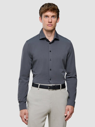 A man wears a Travel Shirt Charcoal Grey Regular tucked into light-colored trousers with a black belt.