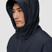A person wearing a hooded black Utility Jacket Black with the hood pulled up over their head.