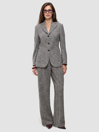 A model wearing a grey herringbone bouclé blazer with a three-button closure and matching Women Ashryn Pants Wide Domino Herringbone.
