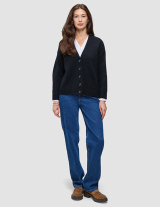 A woman wearing a Women Chunky Soft Wool Knit Cardigan Black over a white collared shirt, paired with blue jeans and brown loafers.