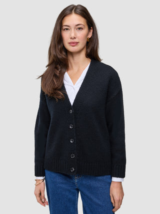 A woman wearing a black Women Chunky Soft Wool Knit Cardigan over a white shirt and blue jeans.