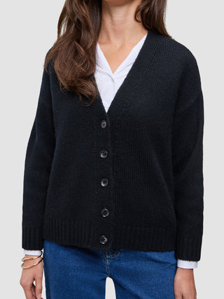 A cozy, chunky Women Chunky Soft Wool Knit Cardigan Black in a V-neck button-down style worn over a white shirt and blue jeans.