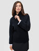 A person wears a Women Chunky Soft Wool Knit Turtleneck Black with white cuffs visible at the wrists, reflecting a clean Scandinavian design.