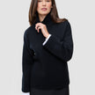 A person wears a Women Chunky Soft Wool Knit Turtleneck Black with white cuffs visible at the wrists, reflecting a clean Scandinavian design.