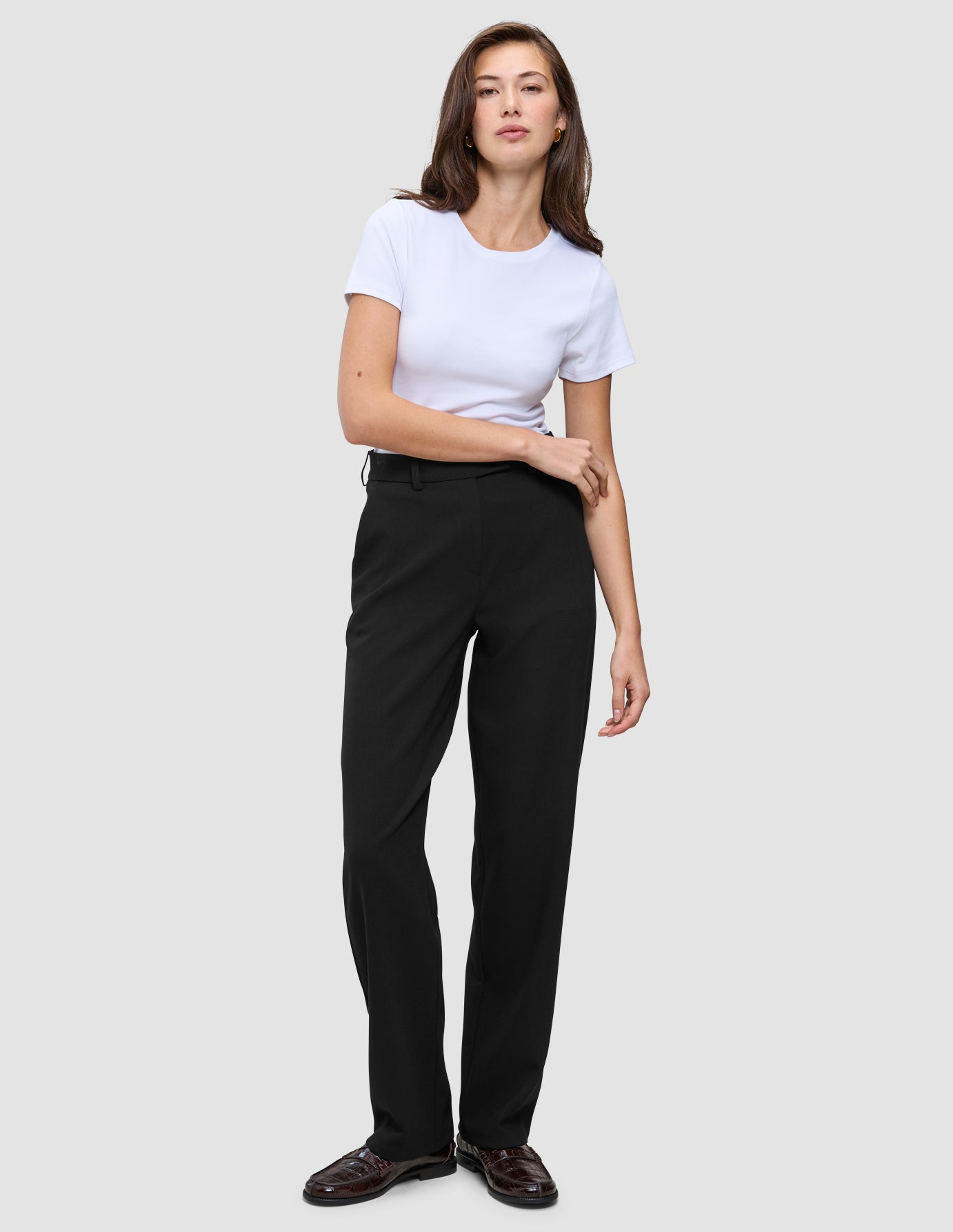 A woman wearing a white t-shirt, Women GO2 Pants Straight Black, and dark loafers.