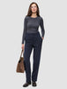 A woman wearing a gray long-sleeved shirt and Women GO2 Pants Straight Blue Nights, holding a brown handbag.