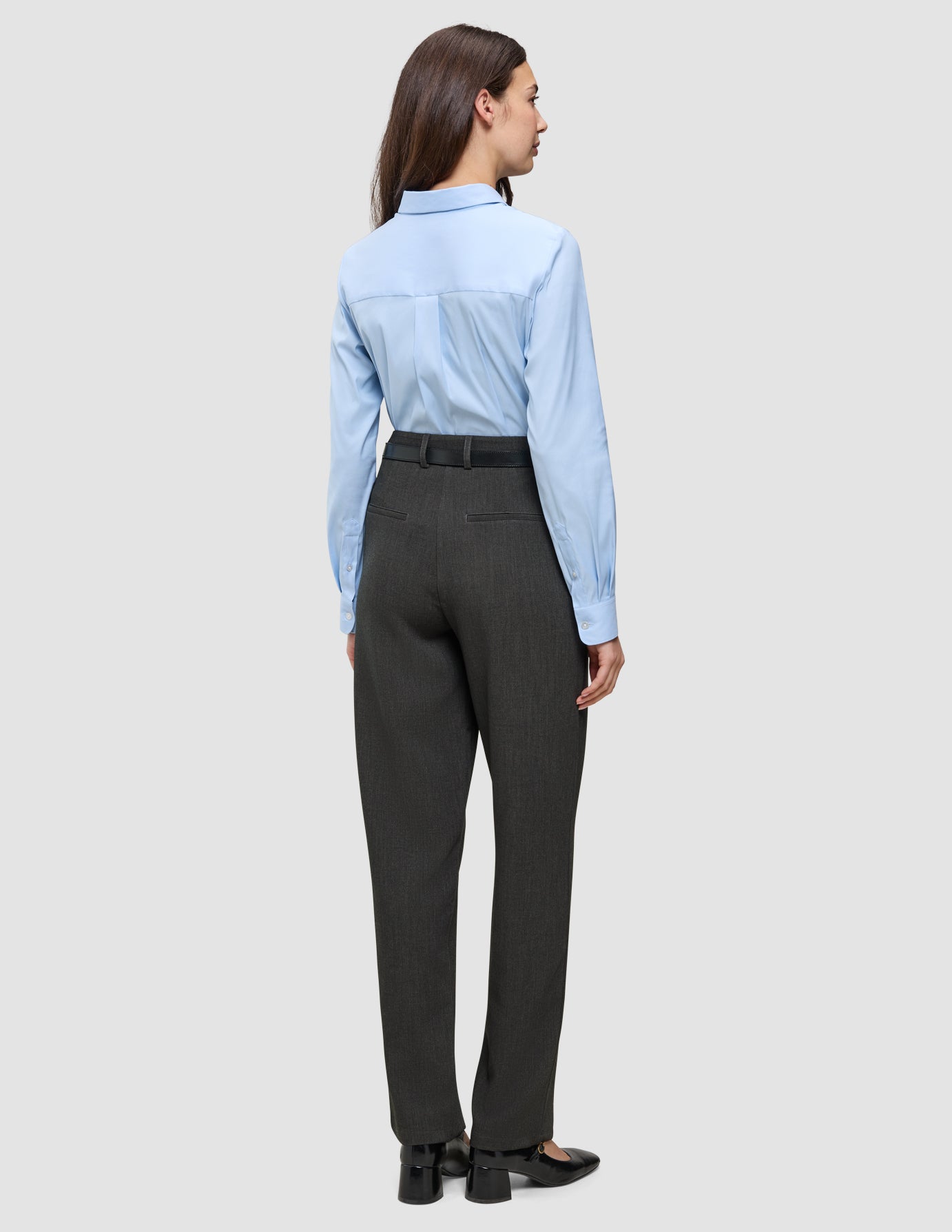 A woman viewed from behind, wearing a light blue button-up shirt and Women GO2 Pants Straight Dark Grey Melange with a black belt.
