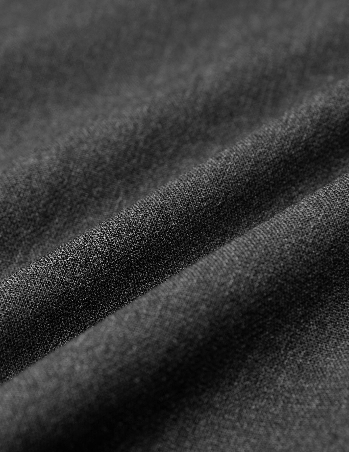 Close-up of Women GO2 Pants Straight Dark Grey Melange, showing draped, dark grey fabric with a visible weave characteristic of Scandinavian design.
