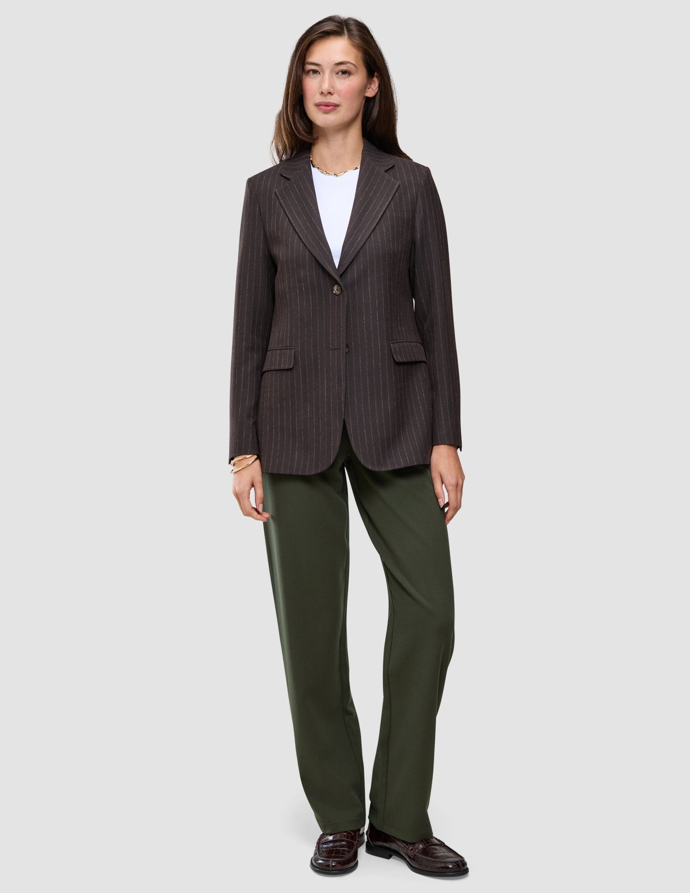 A person wearing a pinstripe blazer over a white t-shirt and Women GO2 Pants Straight Dusty Olive, styled with dark loafers.