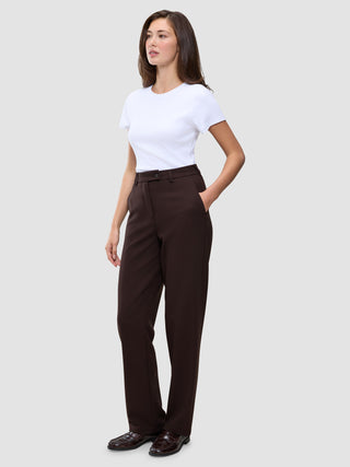 A woman wearing a white t-shirt and Women GO2 Pants Straight Mocha, featuring a high-waisted, straight-leg cut with a button-front waist and side pockets.