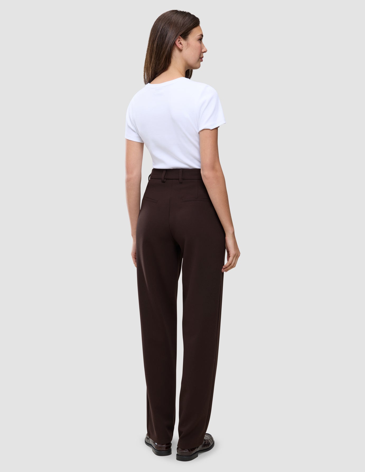 A person viewed from behind, wearing a white t-shirt and Women GO2 Pants Straight Mocha.