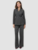 A woman wearing the Women Nara Blazer Fitted Black Check in charcoal gray plaid, paired with matching wide-leg trousers in a Scandinavian design.
