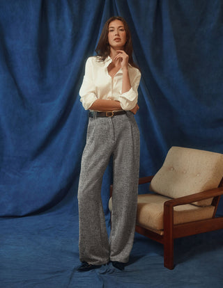 A woman wears a Women’s Oxford Shirt White Orchid Slim tucked into wide-leg, gray speckled trousers.