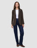 A woman wears a Women Serene Blazer Regular Walnut Herringbone over a white t-shirt, dark wash jeans, and brown heeled boots.