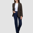 A woman wearing a Women Serene Blazer Regular Walnut Herringbone, white t-shirt, and dark blue jeans.