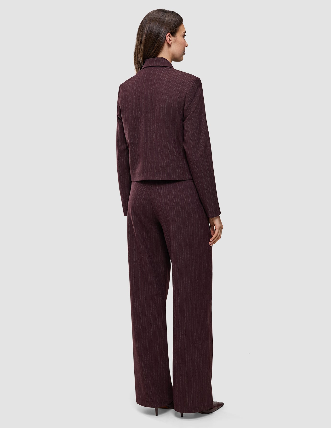 A person seen from behind wears the Women Serene Short Jacket Berry Pinstripe and matching wide-leg trousers in a Scandinavian design.