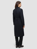 A woman viewed from the back wearing a Women’s Wool Coat Black, featuring a long Scandinavian design with a belted waist.