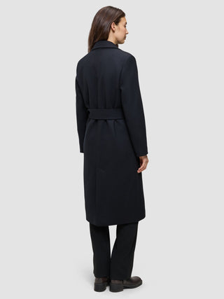 A woman viewed from the back wearing a Women’s Wool Coat Black, featuring a long Scandinavian design with a belted waist.