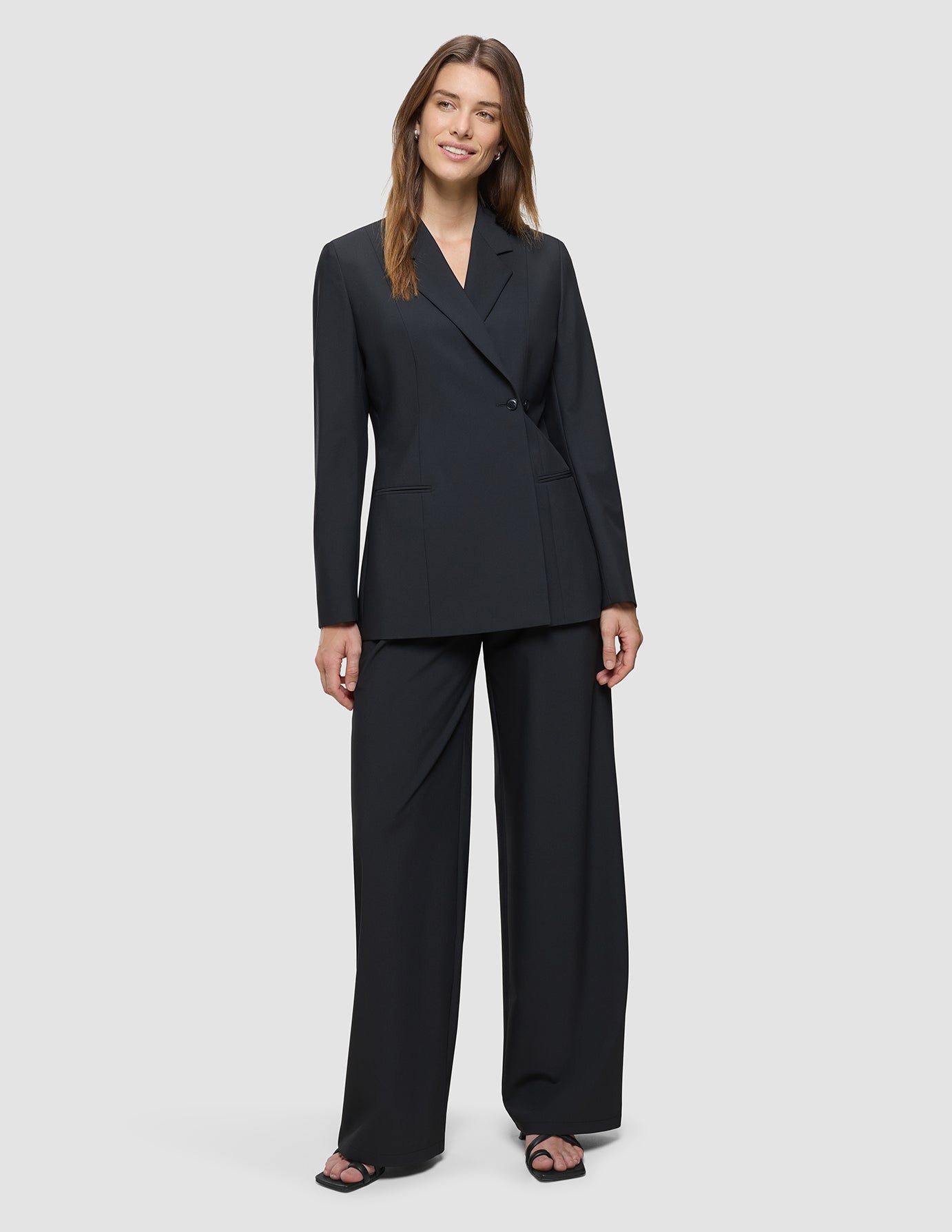 A woman wearing a Women’s Avira Blazer Black in a double-breasted style with matching wide-leg trousers.