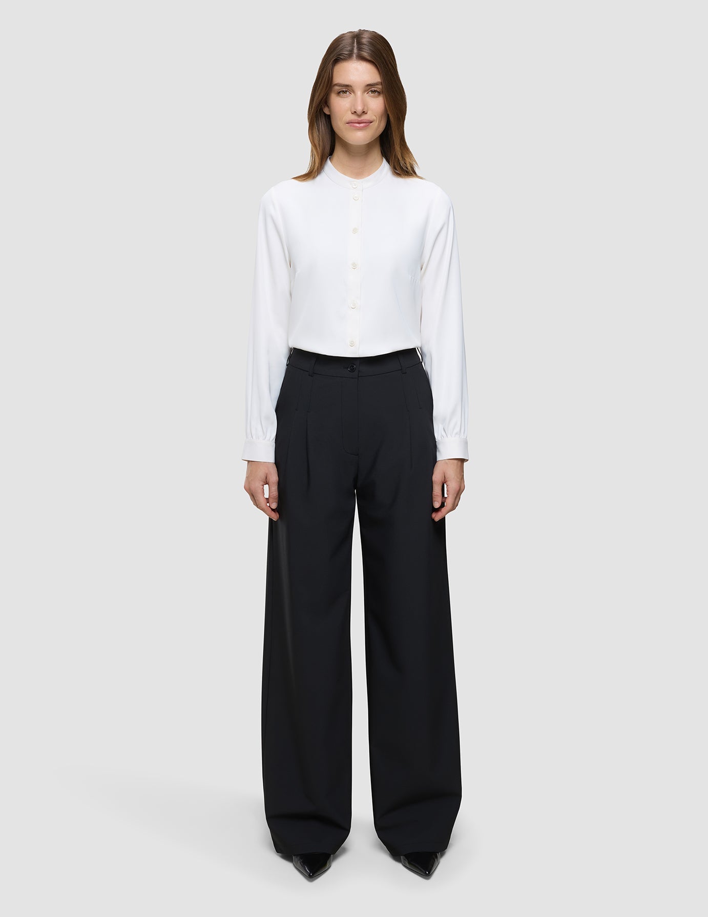 A woman wearing a white button-down shirt with a mandarin collar and Women’s Avira Pants Wide Black.