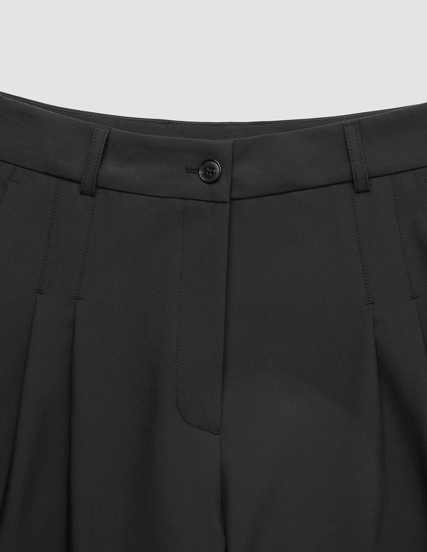 Close-up of the waistband, button closure, and pleated detail of Women’s Avira Pants Wide Black.