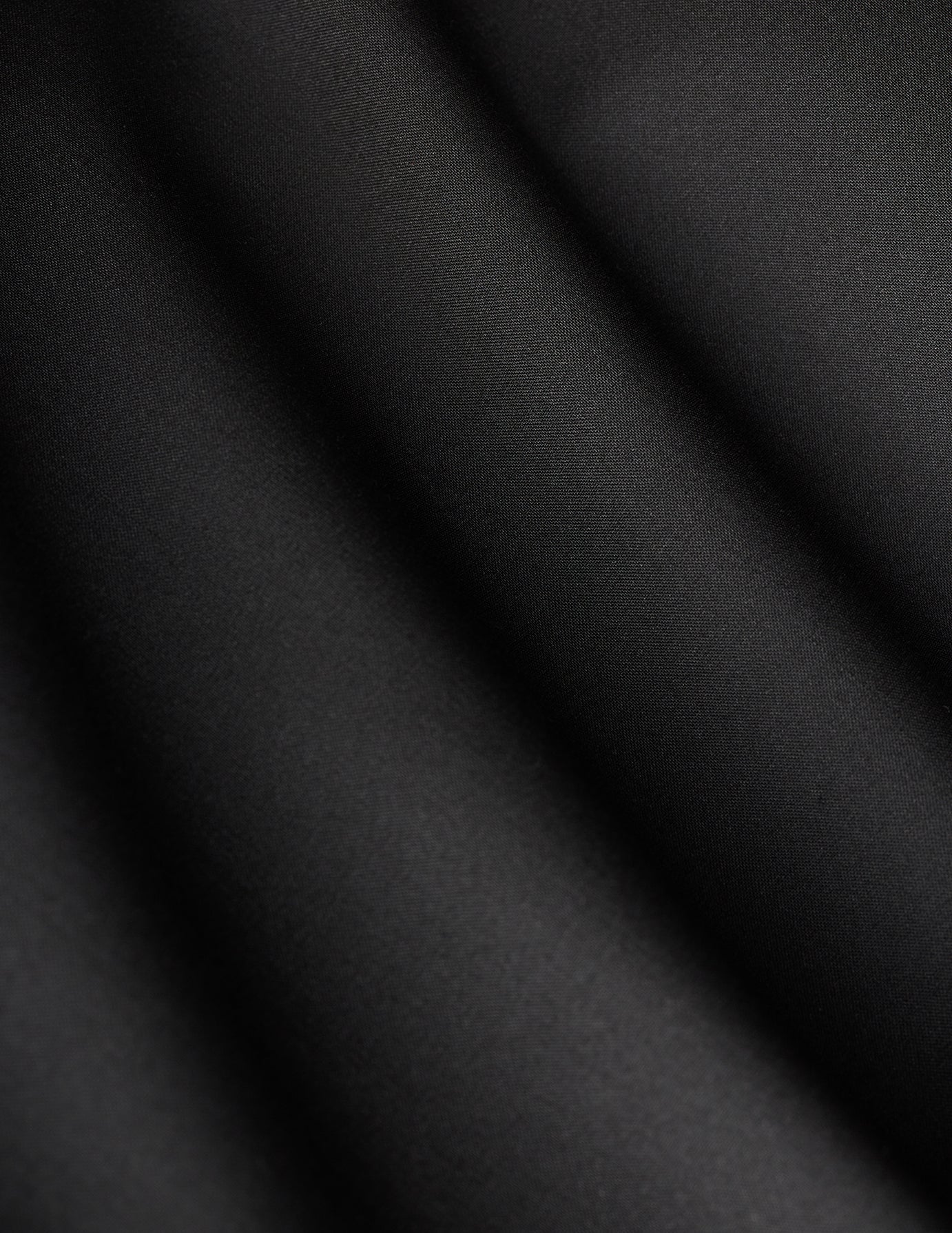 Close-up of black fabric with diagonal folds on Women’s Avira Pants Wide Black.