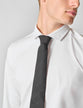 Model wearing a black tie knotted in a full windsor knot close up