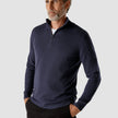 Model seen from the front wearing a navy blue half zip in fine knit with a white shirt underneath