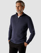 Model seen from the front wearing a navy blue half zip in fine knit with a white shirt underneath