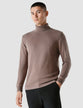 Model seen from the front wearing an almond brown turtleneck in fine knit 