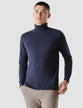 Model seen from the front wearing a navy blue turtleneck in fine knit 