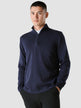 Model seen from the front wearing a navy blue half zip in fitted knit with a white shirt underneath