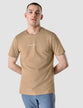Model wearing sand grain t-shirt seen from the front the t-shirt has the company logo across the chest