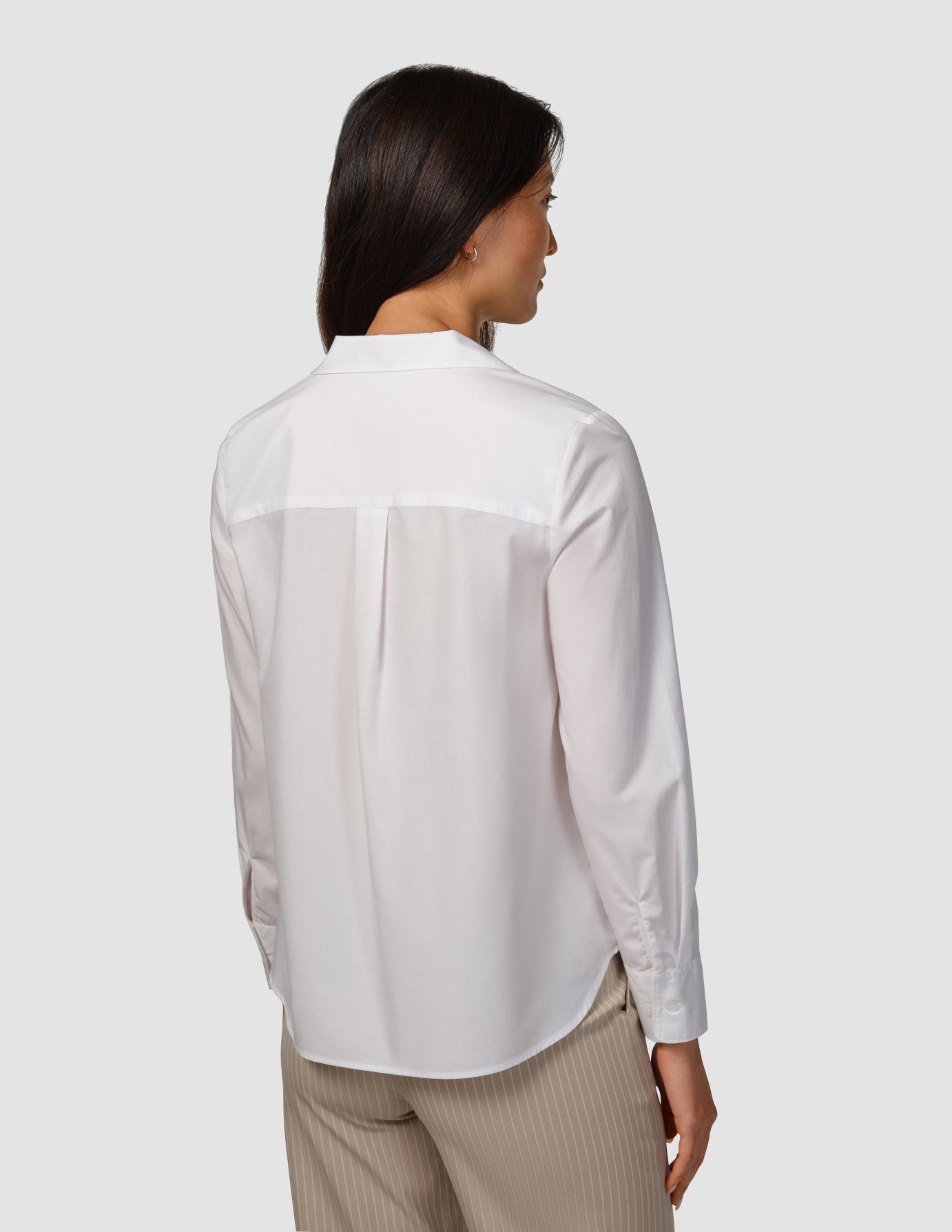 Back view of a person wearing a Madison Shirt White and pinstriped trousers, embodying a clean Scandinavian design.