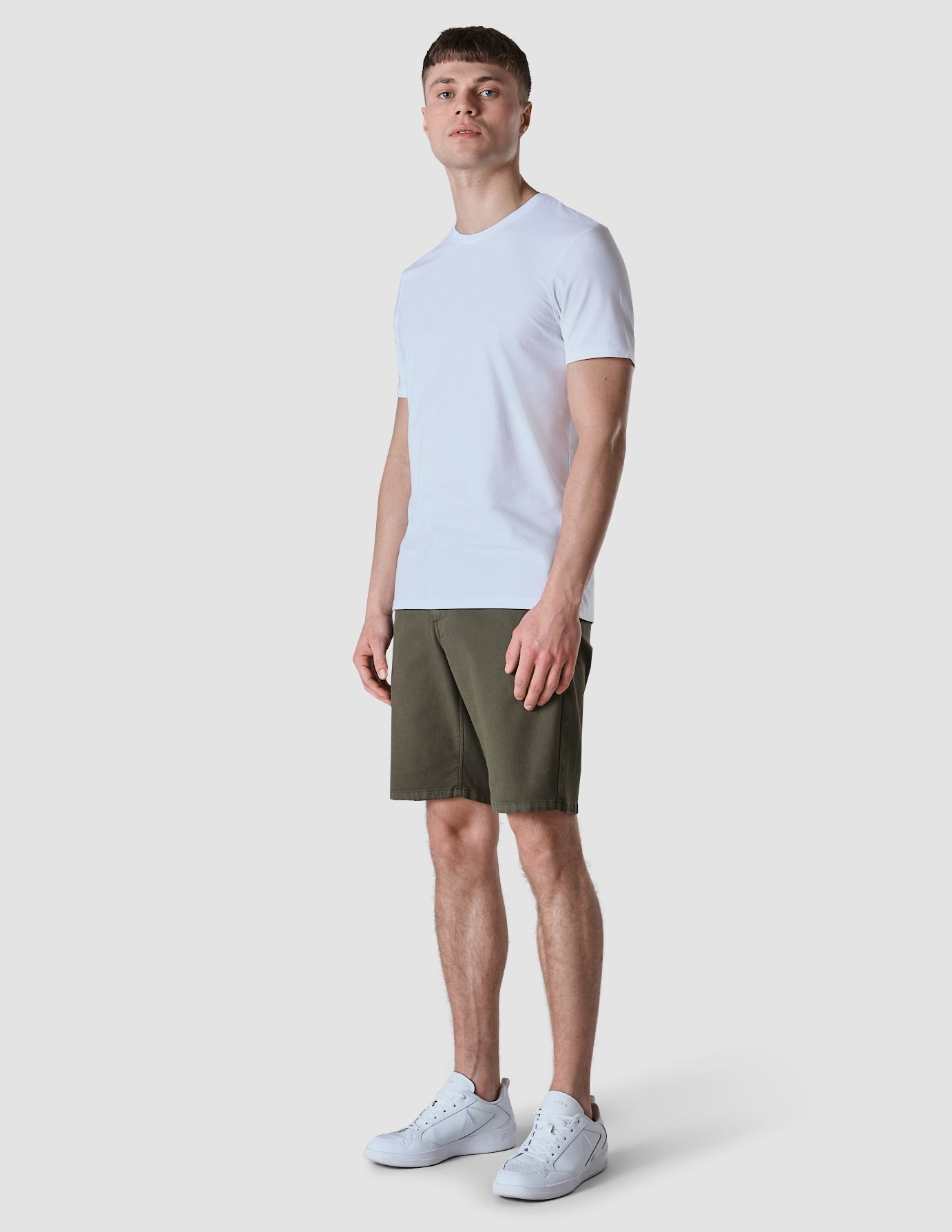 Model in full body wearing Classic Shorts urban green shorts with a white t-shirt