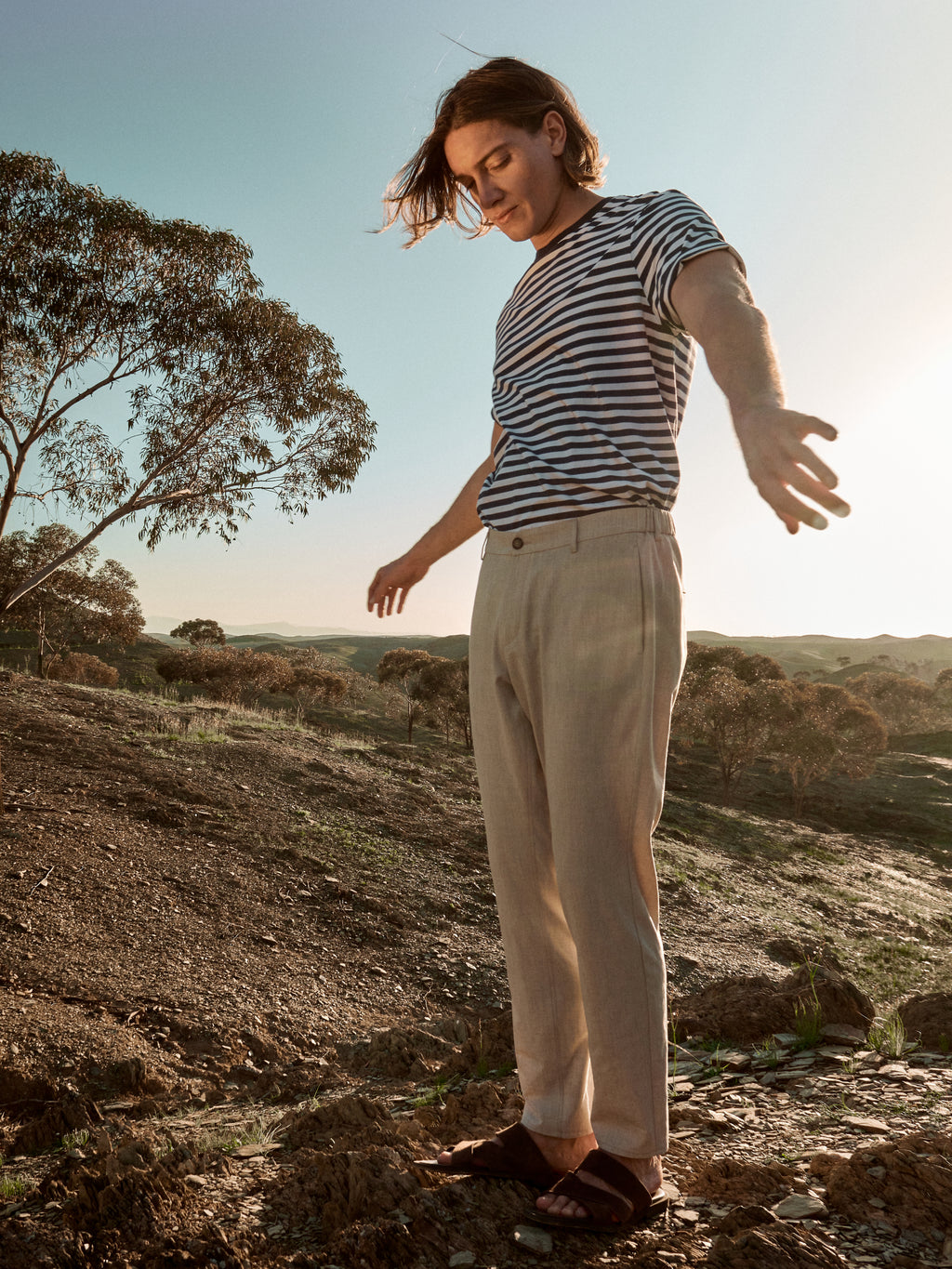 Male model wearing beige pants and striped T-shirt in a desert