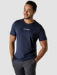 Model wearing navy t-shirt seen from the front the t-shirt has the company logo across the chest