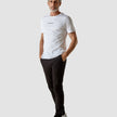 Model in full body wearing white t-shirt with black pants and white sneakers, the t-shirt has the company logo across the chest