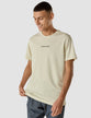 Model wearing dunes/beige t-shirt seen from the front the t-shirt has the company logo across the chest
