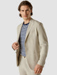 Model from the front wearing a Tech Linen Blazer Sandshell with a striped t-shirt underneath and with matching pants